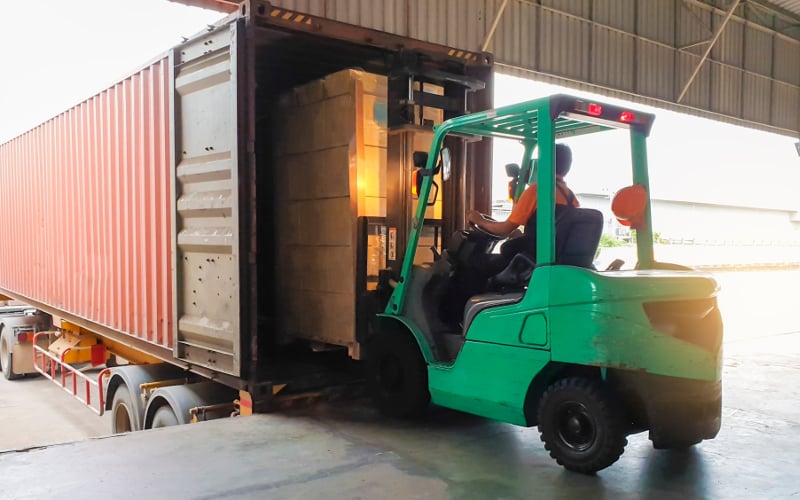 A forklift loading a truck and trailer